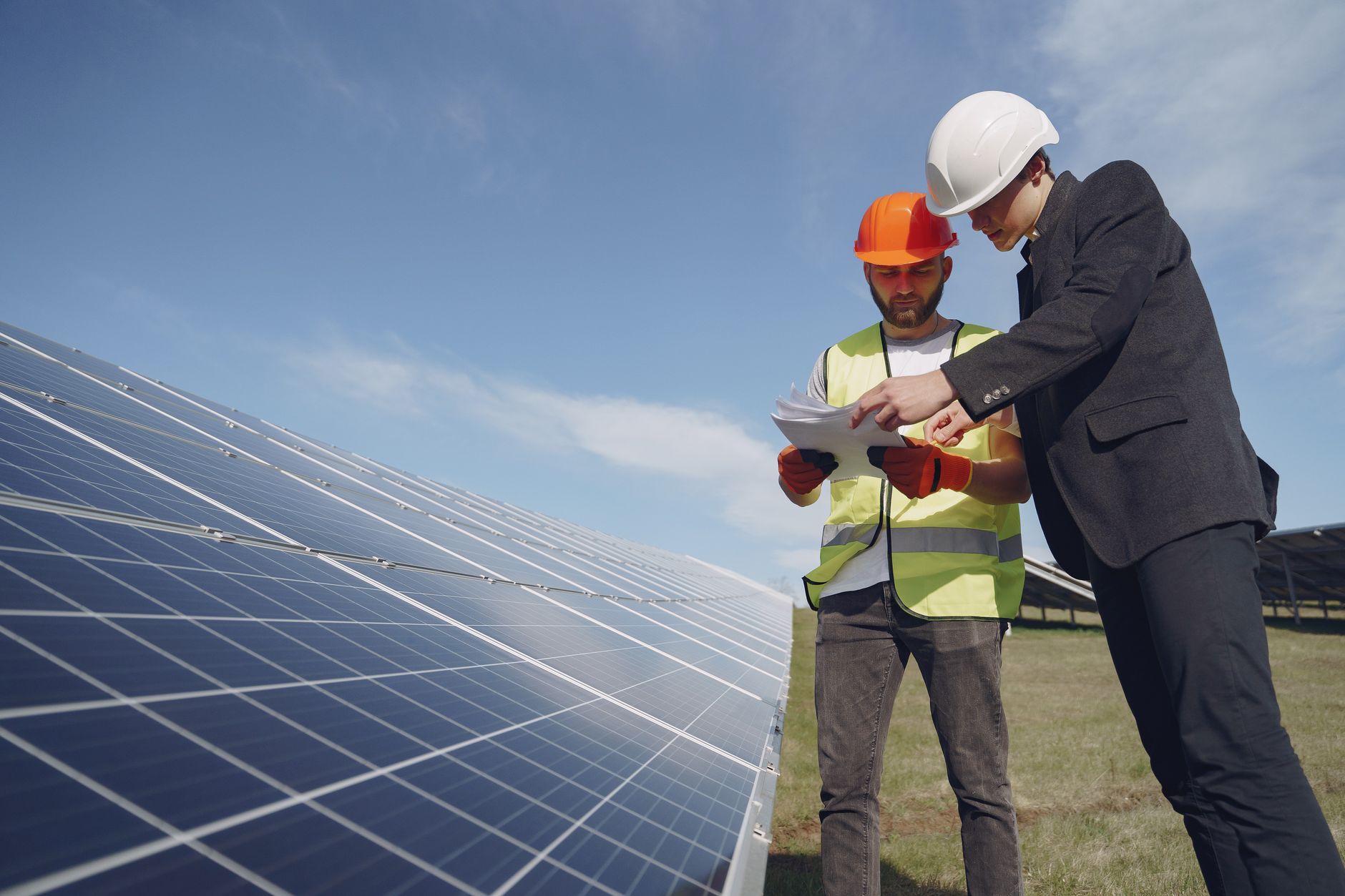Inspector and manager checking documentation by a solar panel array